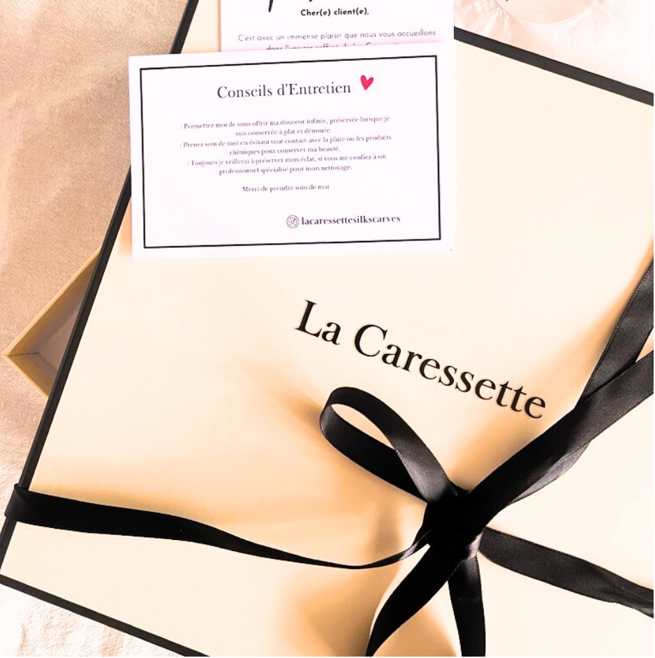 Beigefarbene Geschenkbox von La Caressette mit schwarzem Band.
