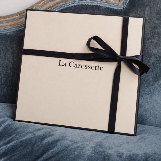 Écrin La Caressette au ruban noir sur un fauteuil bleu